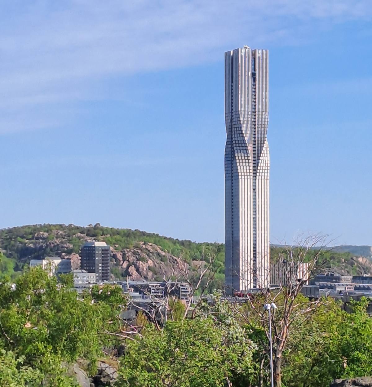 A single monolithic tower rising sheer above a low city skyline, dwarfing every structure around it